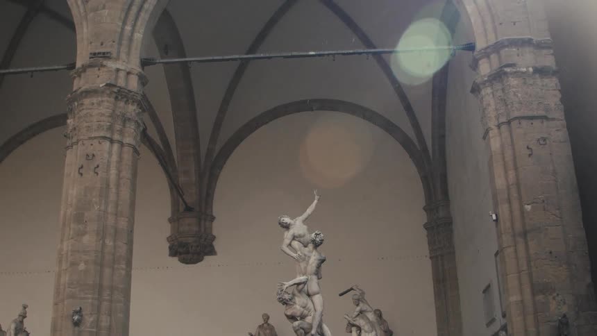 Marble statues stand beneath grand stone arches in an open gallery