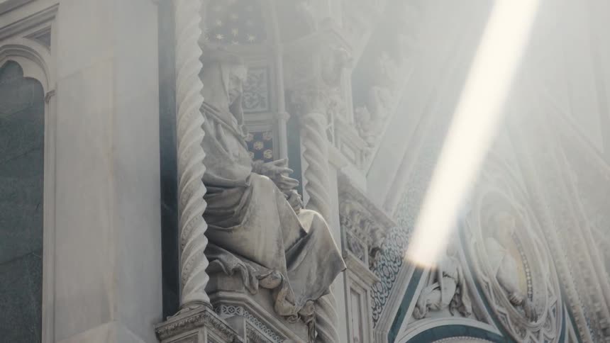 The sun flares on the statues on the church
