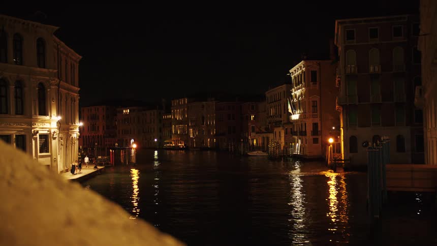 Canal surrounded by historic buildings illuminated at night reflecting lights on the water