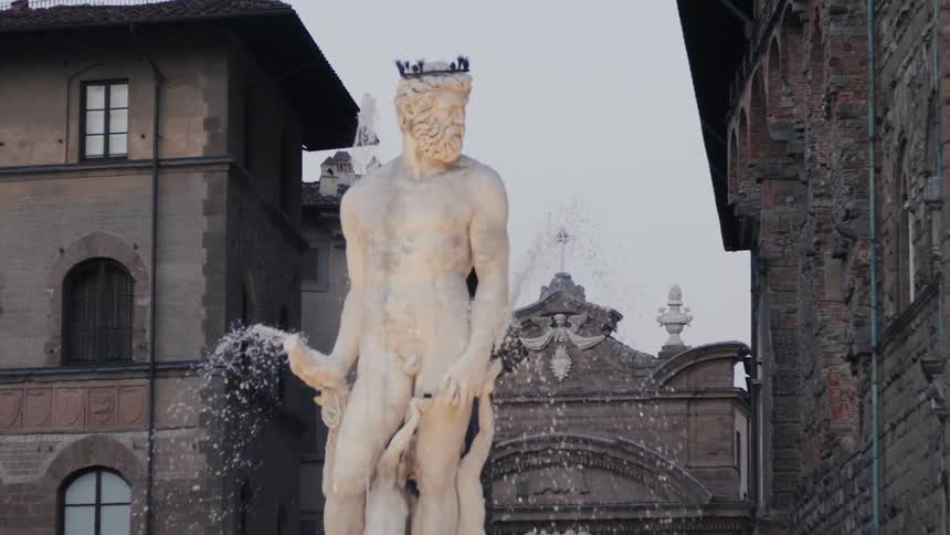 The video features a closeup of a large white marble statue of a bearded male figure likely neptune standing in a fountain with water spraying around its base the sculpture is set in a historic city square framed by the surrounding