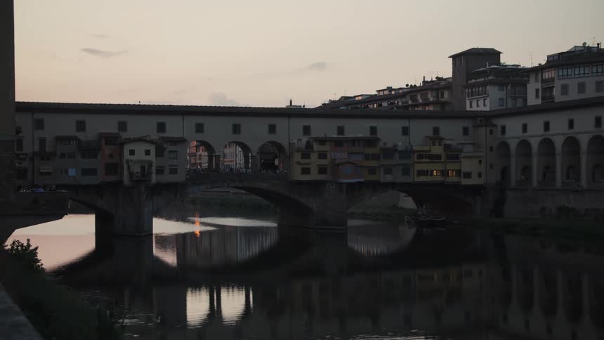 Ponte vecchio over the arno river with buildings along the structure reflected in the water
