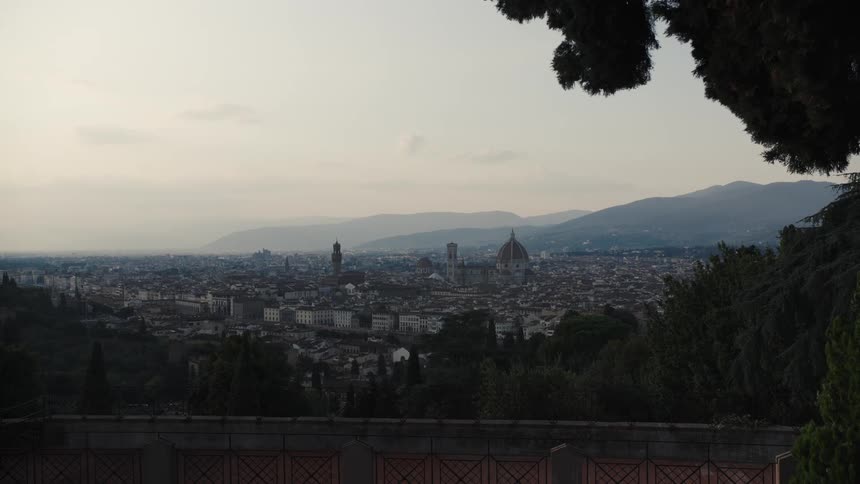 Florence cathedral dome stands out among historic buildings with hills in the background and greenery in the foreground