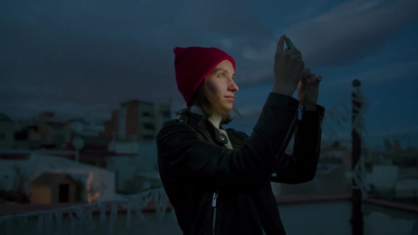 Woman in a red beret captures the sunset with her phone