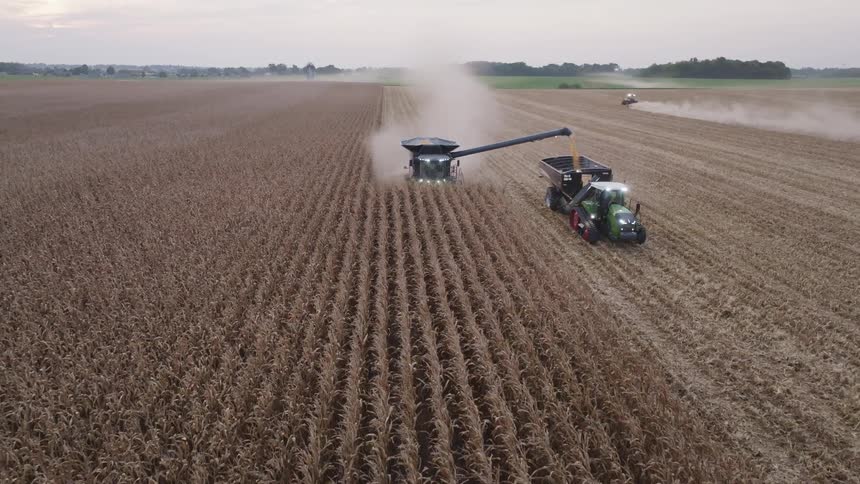 Combine harvester unloading grains into a trailer while moving through the crop field