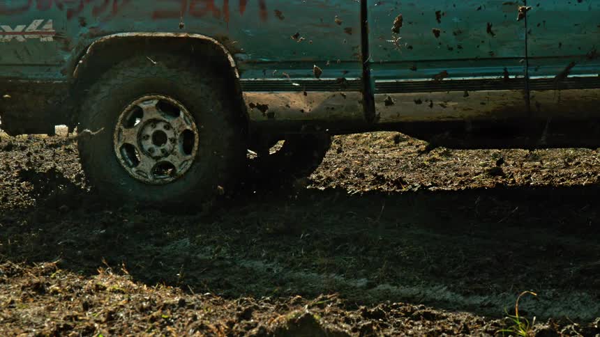 Mudcovered pickup truck driving through a muddy terrain