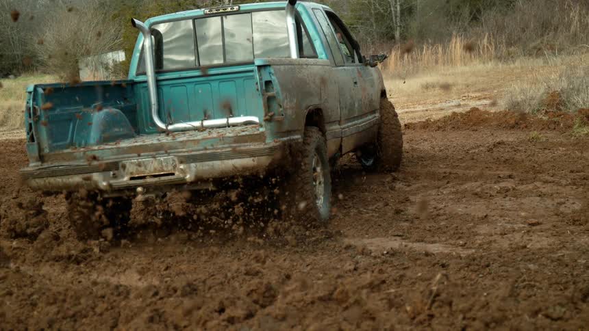 Pickup truck splashing mud while driving through wet terrain
