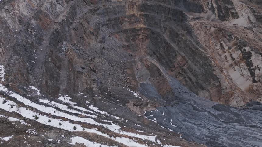 Steep hillside with rocky layers and sparse trees at the base