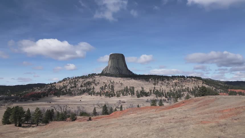 Desert landscape with a large rock surrounded by sparse vegetation during daytime