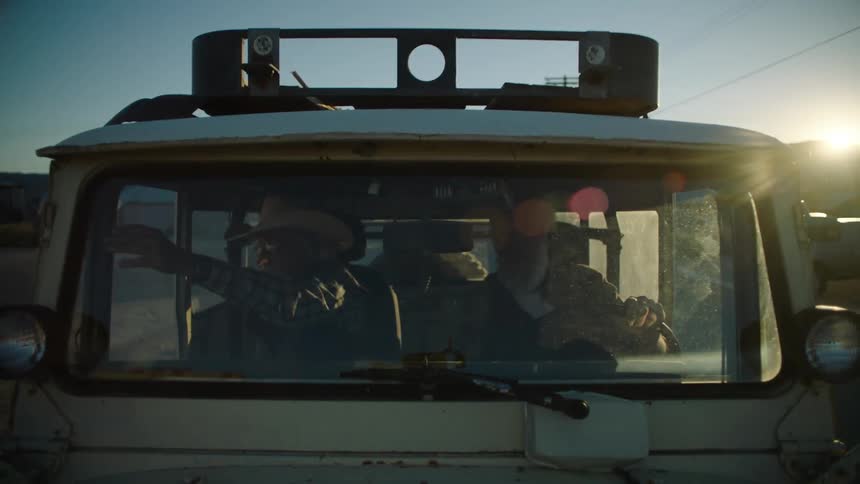 A couple of people driving an old truck or jeep and then stopping