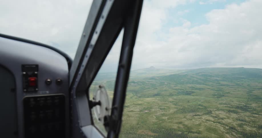 Aerial view of green hills through an airplane window in flight