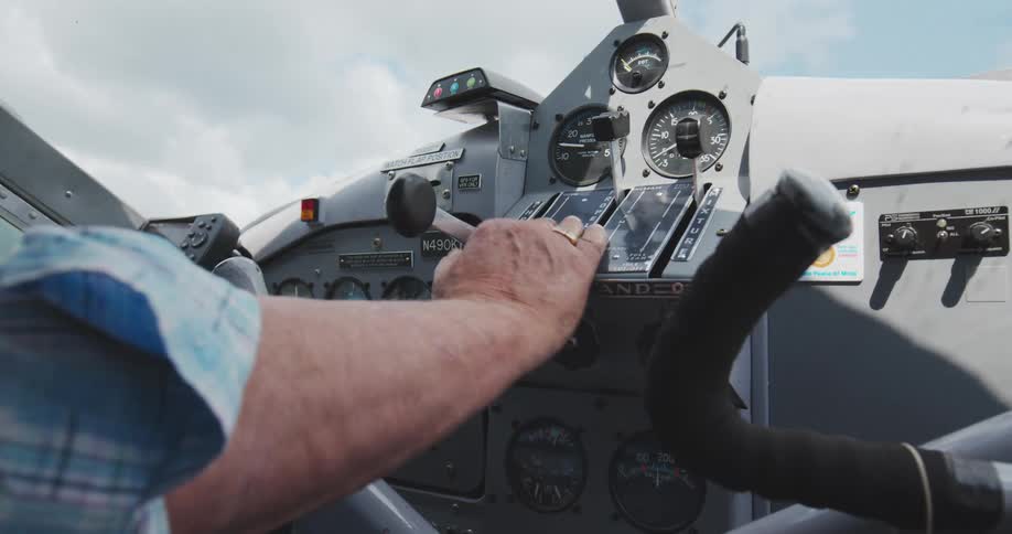 Pilot adjusting controls on an aircraft cockpit panel