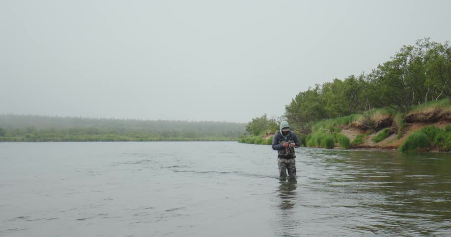 Man outdoors fishing with his knees covered in water during day time