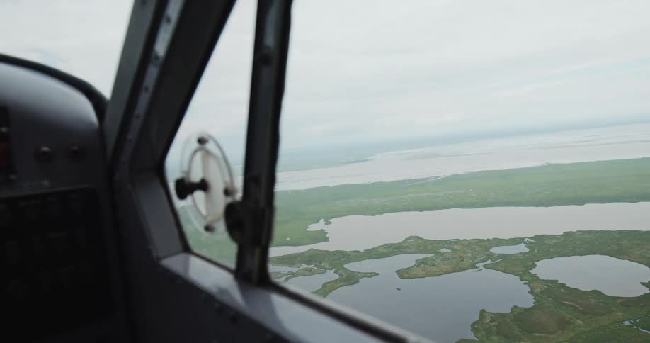 Aerial view of lakes and greenery seen through the side window of an aircraft