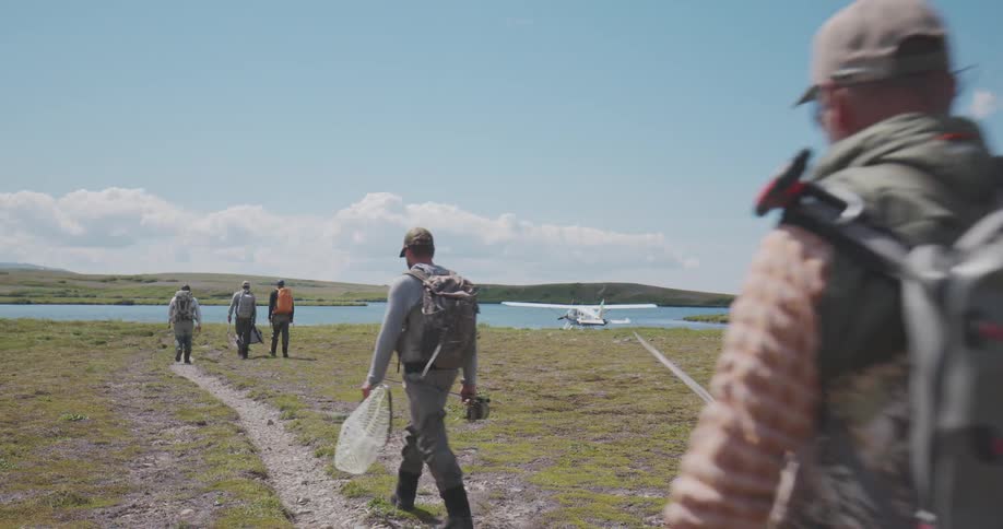 Fishermen walking toward a seaplane by the lakeshore