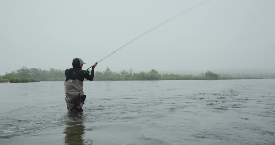 Lone fisherman casts a line in a misty river