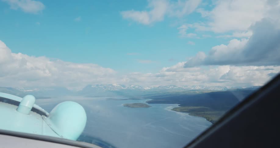 Aerial view of a winding river and mountains in the background from an airplane cockpit
