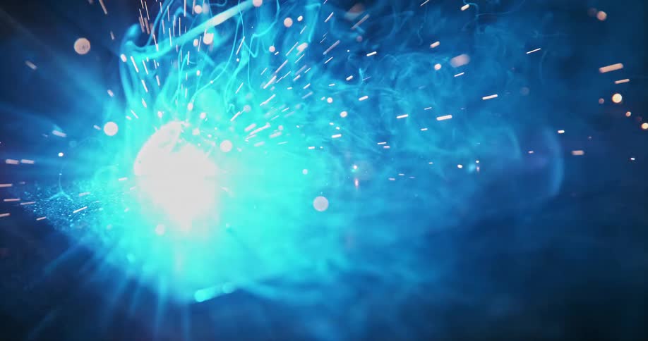 Welding in progress with bright blue sparks and smoke illuminating the metal