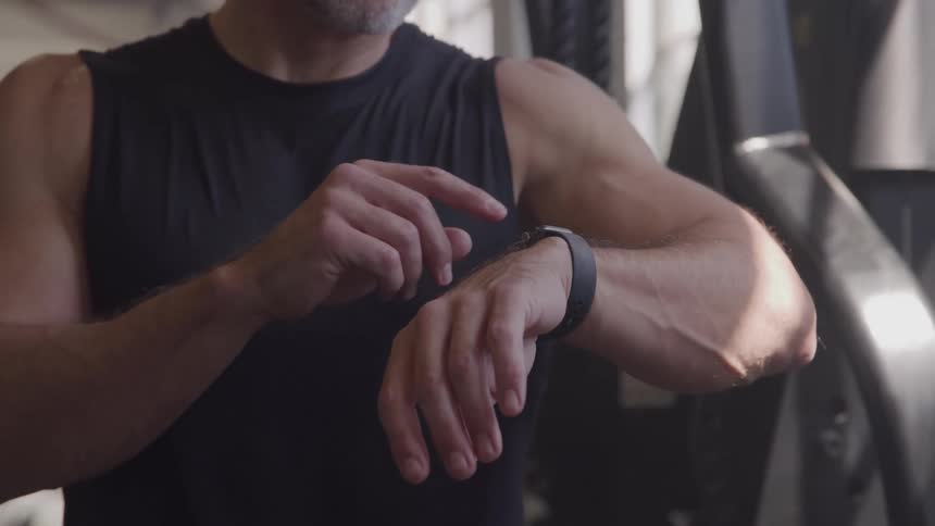 Man in workout clothes using a smartwatch at the gym
