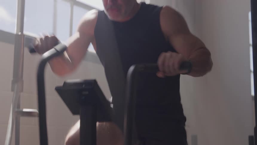 Man focused on pedaling a stationary bike during a workout
