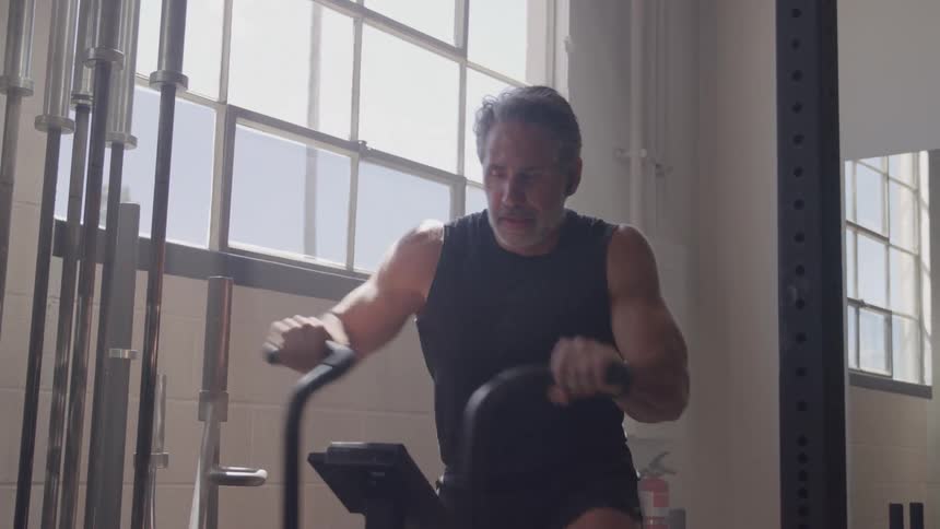 Man working out on a stationary bike in a gym lit by natural light