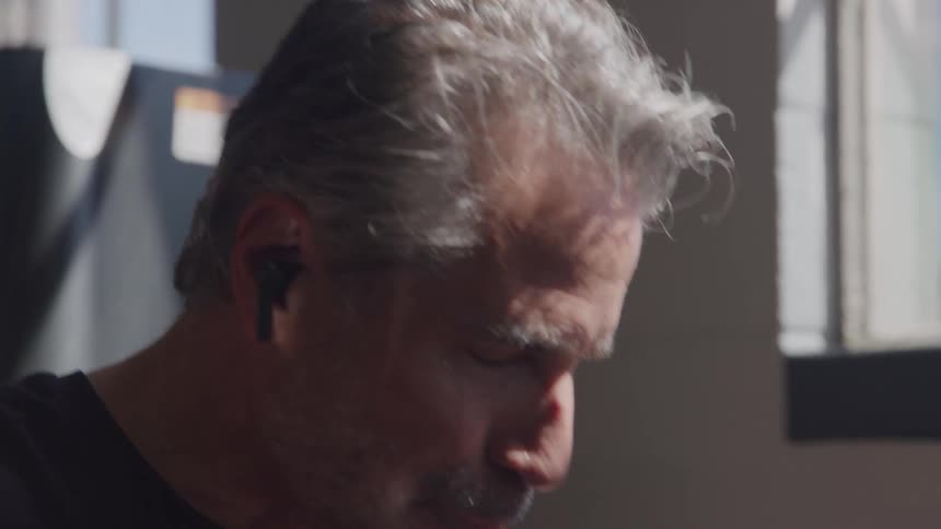 A sweaty middleaged man with graying hair and a beard takes a break from his workout drinking water and catching his breath