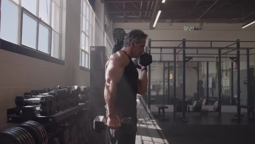 Man lifting dumbbells during strength training in a welllit gym