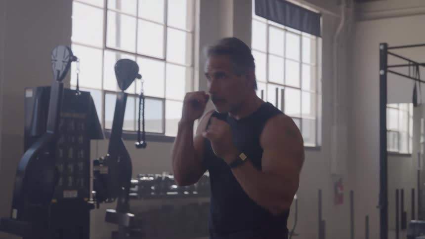 Close up of a middle aged man training combat punches in a gym during daytime