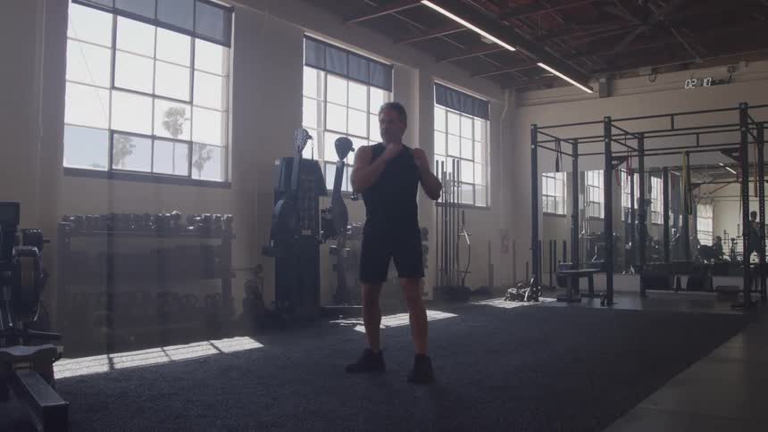 A middleaged man stretches his body back and forth in the gym at midday focusing on flexibility and movement