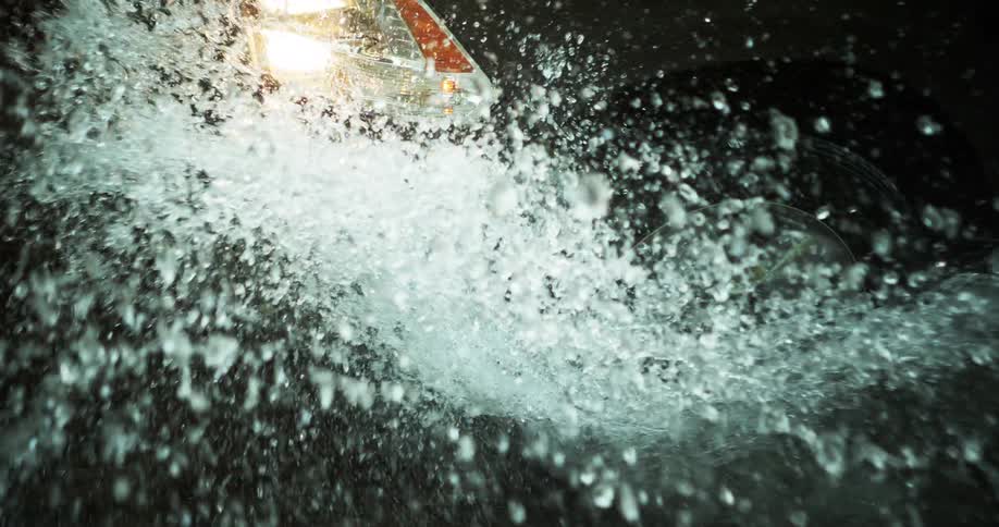 Pickup truck wheel splashing water while driving through a puddle at high speed