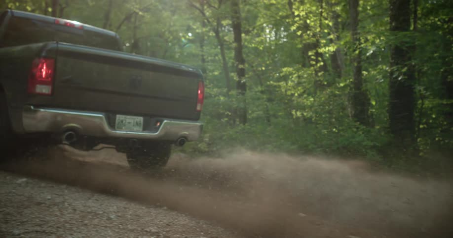 An off road truck driven on a sandy road in a woodland during daytime