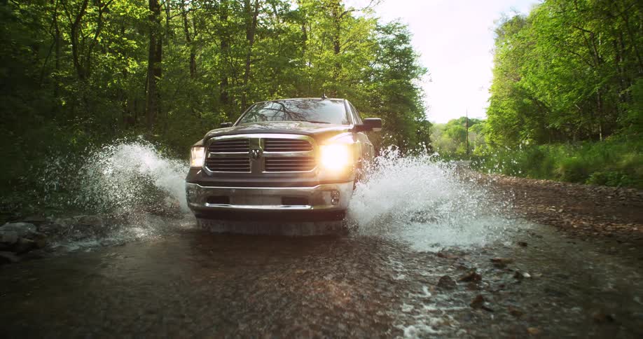 The large truck drives through the creek