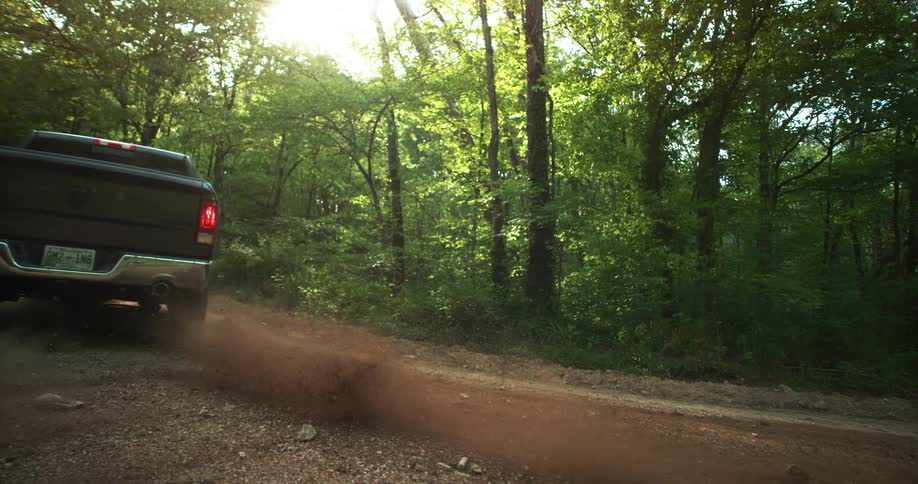 Pickup truck parked on a dirt road surrounded by forest at sunset