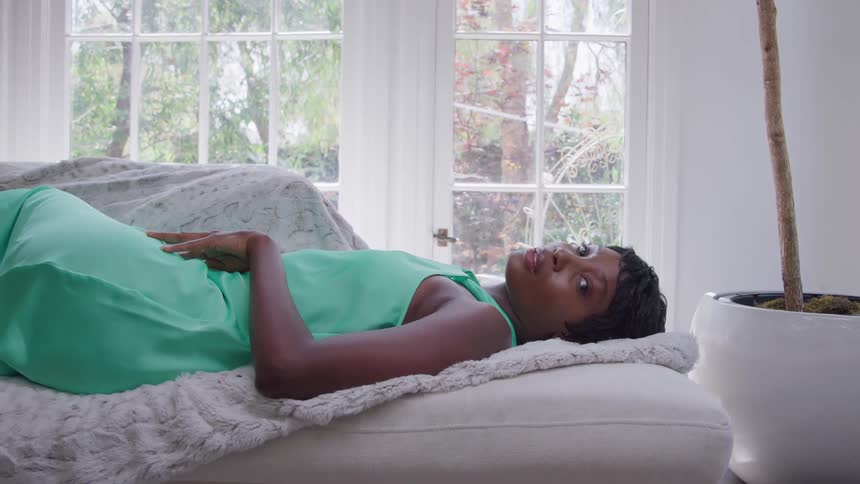 The woman is laying down on a white couch