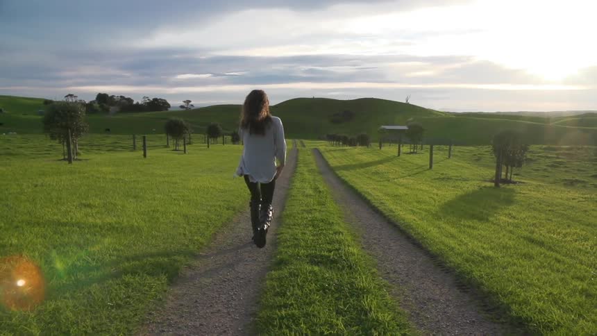 Woman travels down a green field with a small path