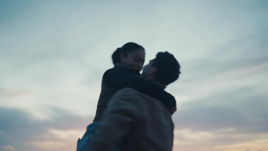 Couple embraces at sunset with mountains in the background