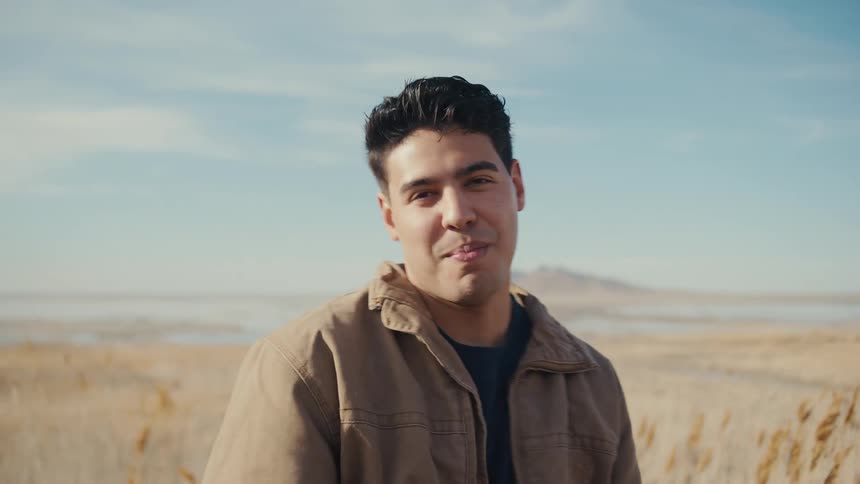 Man posing and smiling outdoors next to a field during day time
