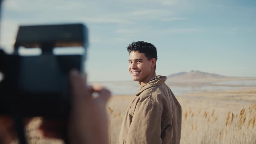 A man models for someone taking pictures in a field