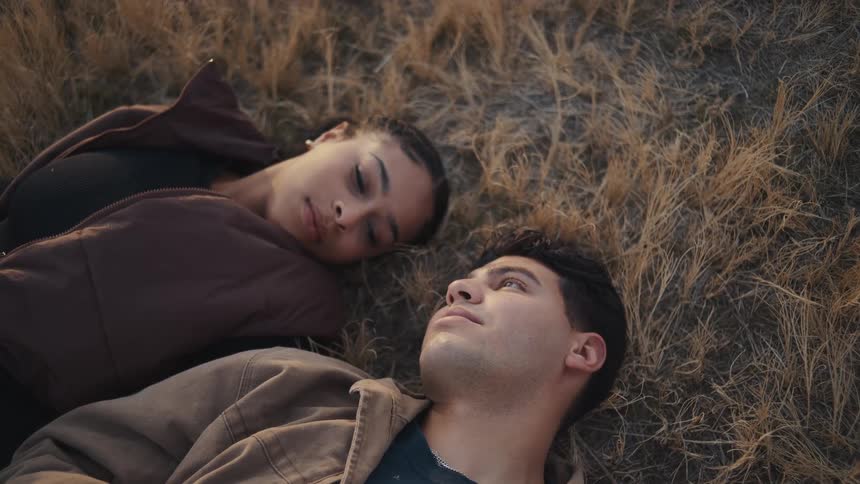 Young couple lies close together in a field on an autumn day