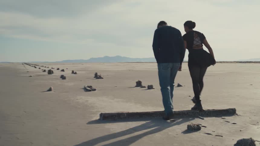 White young man and black young woman walking on a natural landscape surrounded by sand and rocks outdoors during day time