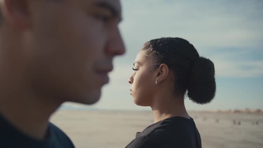 Angry couple stands apart after a fight in a sunlit landscape