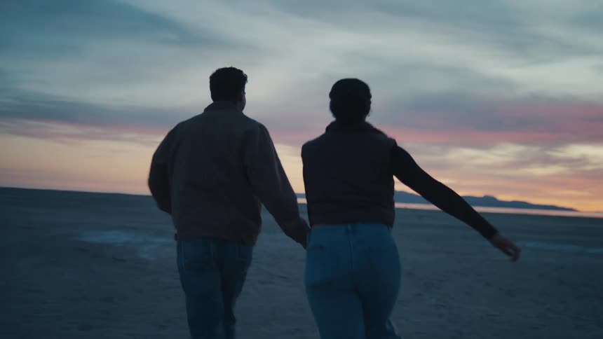 A female and male dance and run happily on a beach