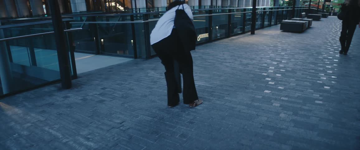 Woman carrying her shoes on her hand while she rushes forward before stopping to put the shoes on and continue walking outdoors during day time