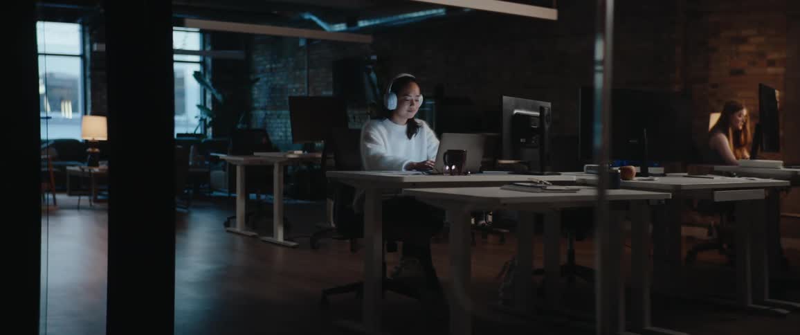 Woman wearing headphones working in an office with soft ambient lighting