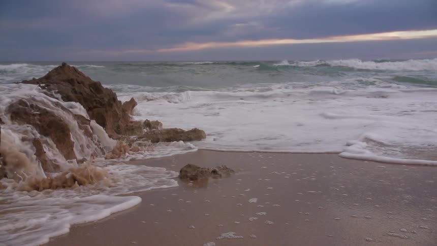 Water rushes over some rocks by the shore