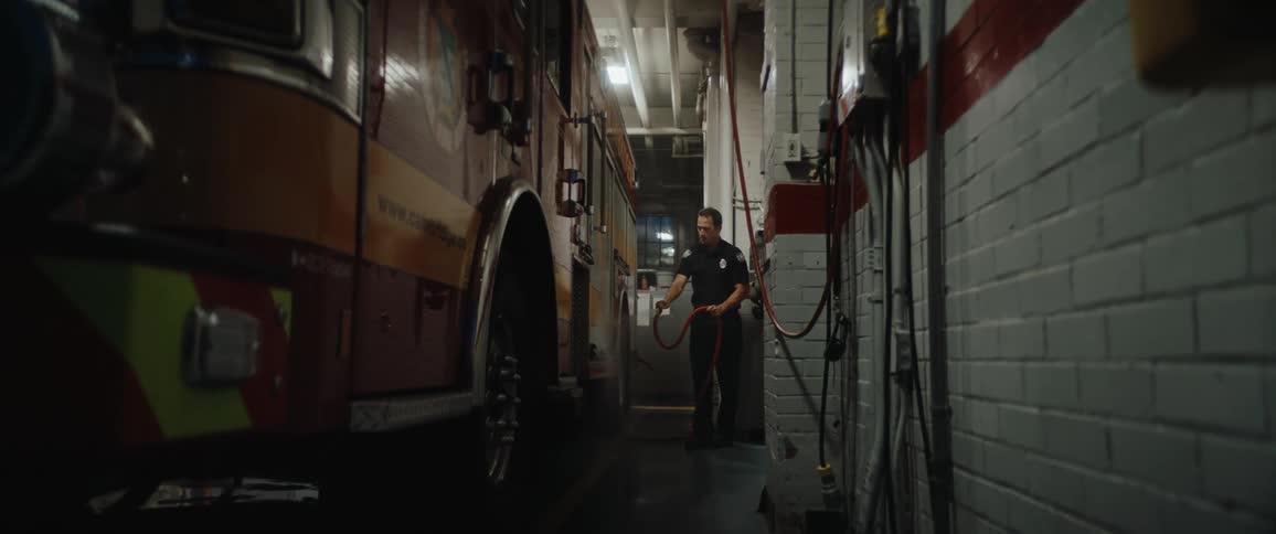Firefighter organizing a hose beside a truck inside the station