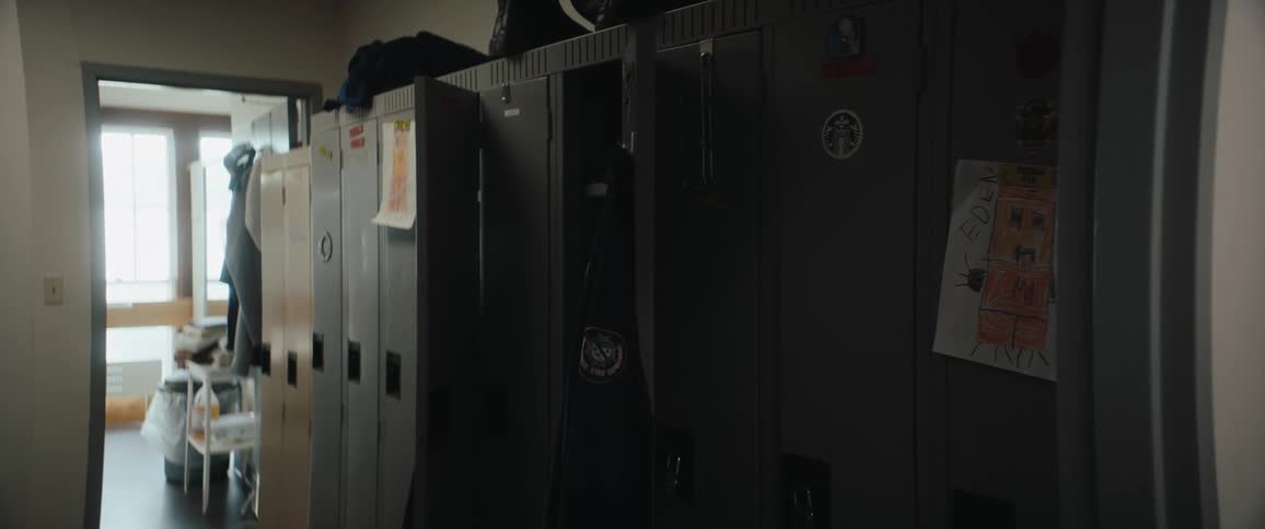 Locker room with a couple of doors opened and pieces of clothing hanging on them indoors during day time