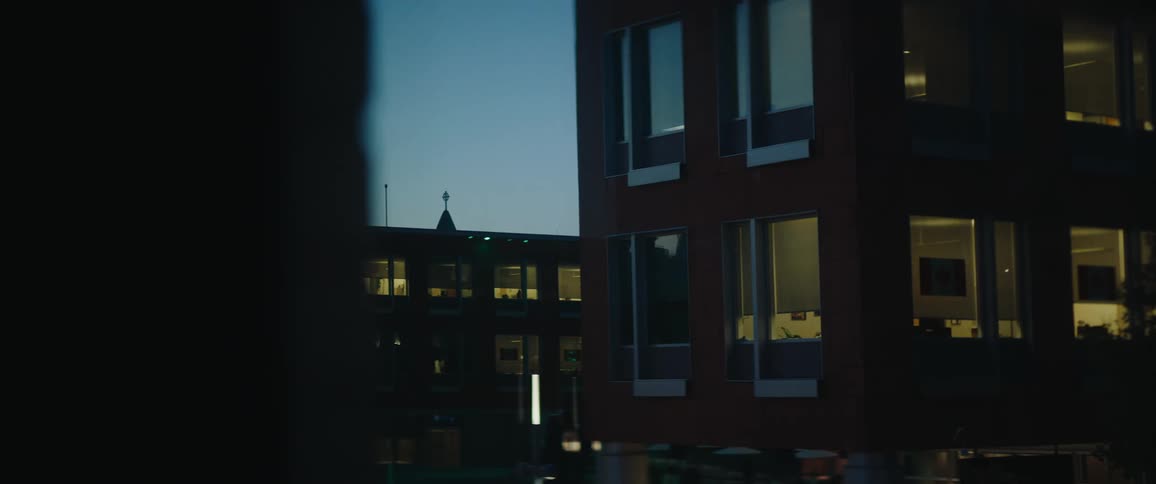 Buildings with lit windows seen at dusk in an urban setting