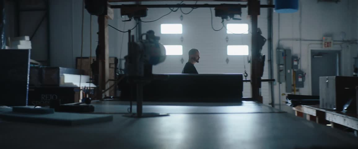 Man working in a workshop lit by light coming through the doors and windows