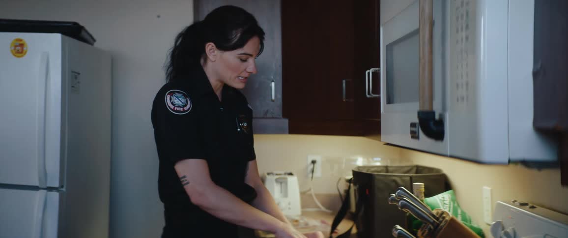 Firefighter slicing tomatoes in a kitchen with utensils arranged on the counter