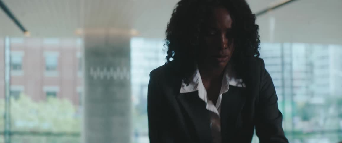 Black woman dressed in formal wear putting glasses over a table on an office indoors during day time